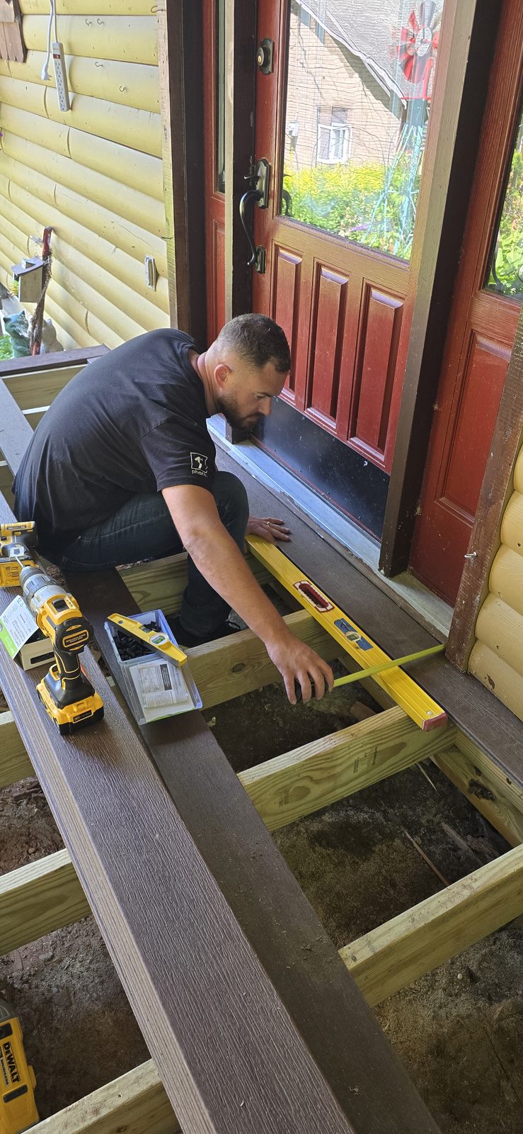 Matthew Pinto checking new porch framing dead-level before the decking goes down